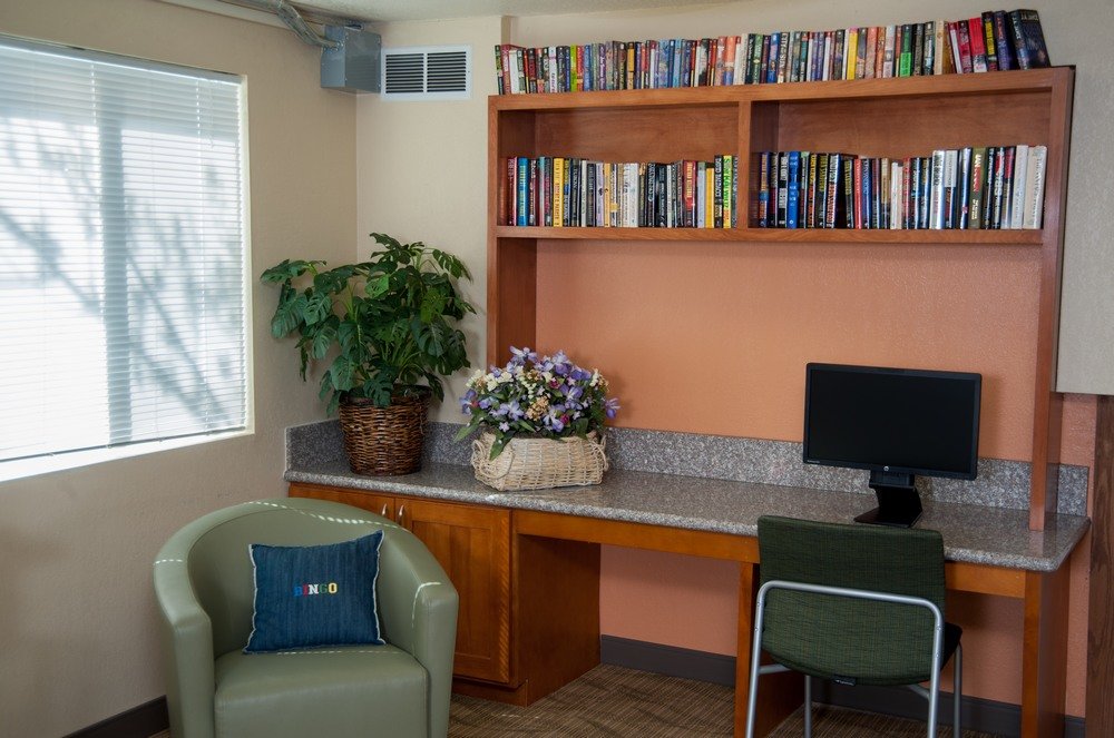 Sala comunitaria con libros y una computadora.