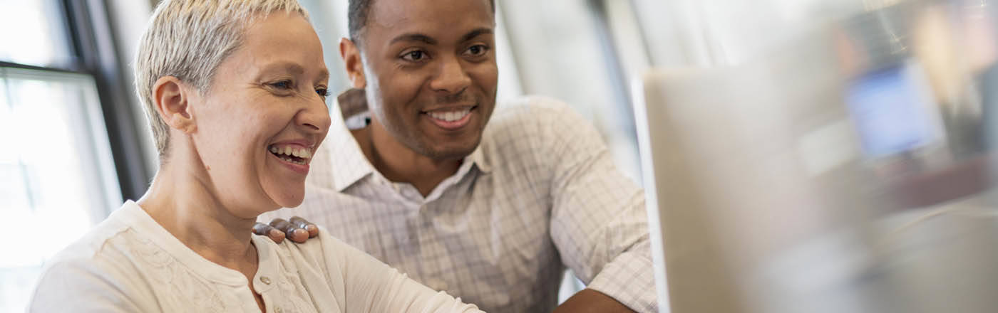 2 coworkers in office smiling at laptop