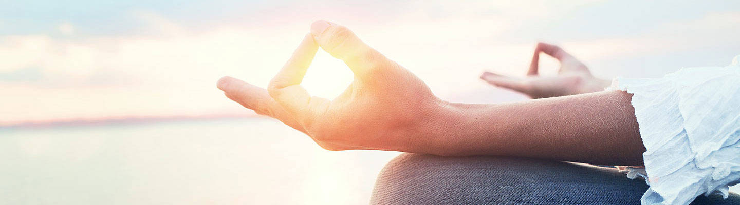 Close up of meditating hands at sunset